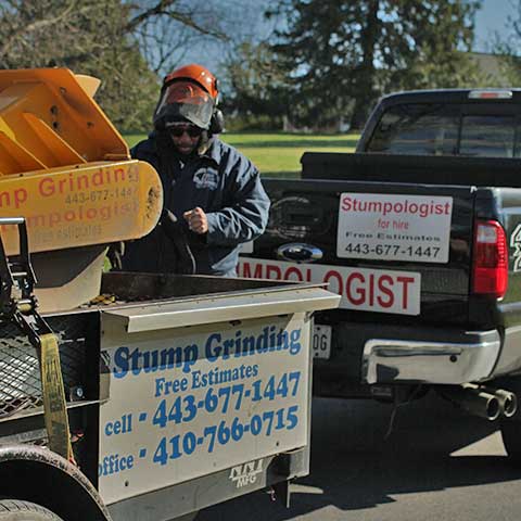 Sam Crowder stands between his Ford pickup truck and the trailer carrying his Carlton stump grinder as he prepares to unload and get to work